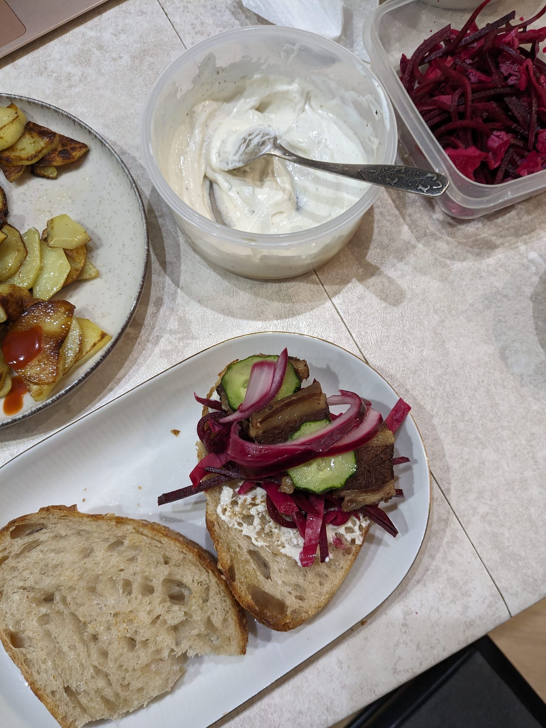 Открытый бутерброд с мясом, огурцом и маринованным красным луком; рядом жареная картошка, соус и маринованный красный лук